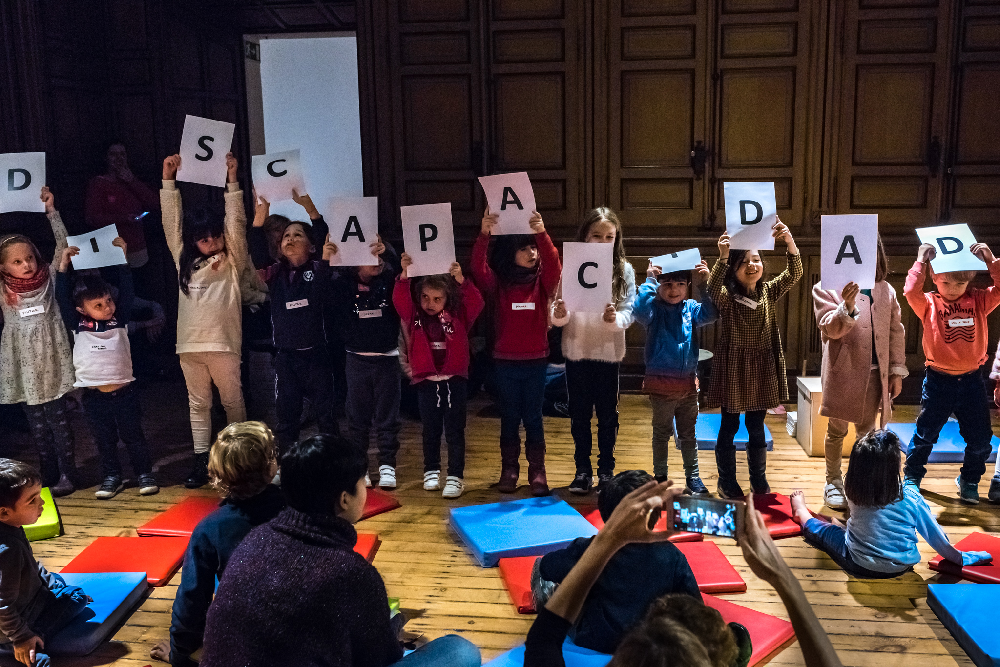 Vista frontal de un grupo de niñas y niños sosteniendo las letras que forman la palabra ´discapacidad´. 
